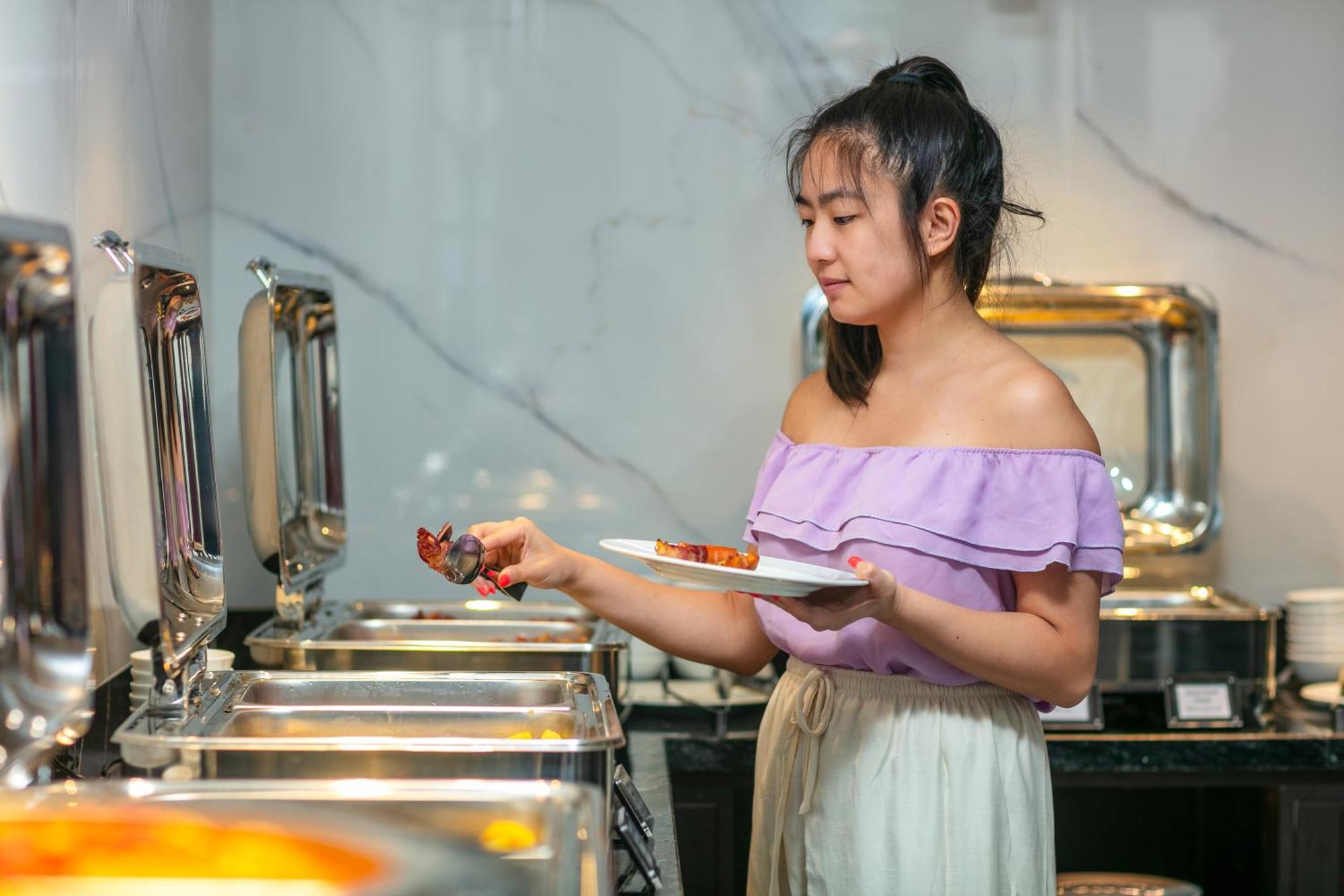 May De Ville Lakeside Hotel Hanoj Exteriér fotografie A woman serving herself at a buffet